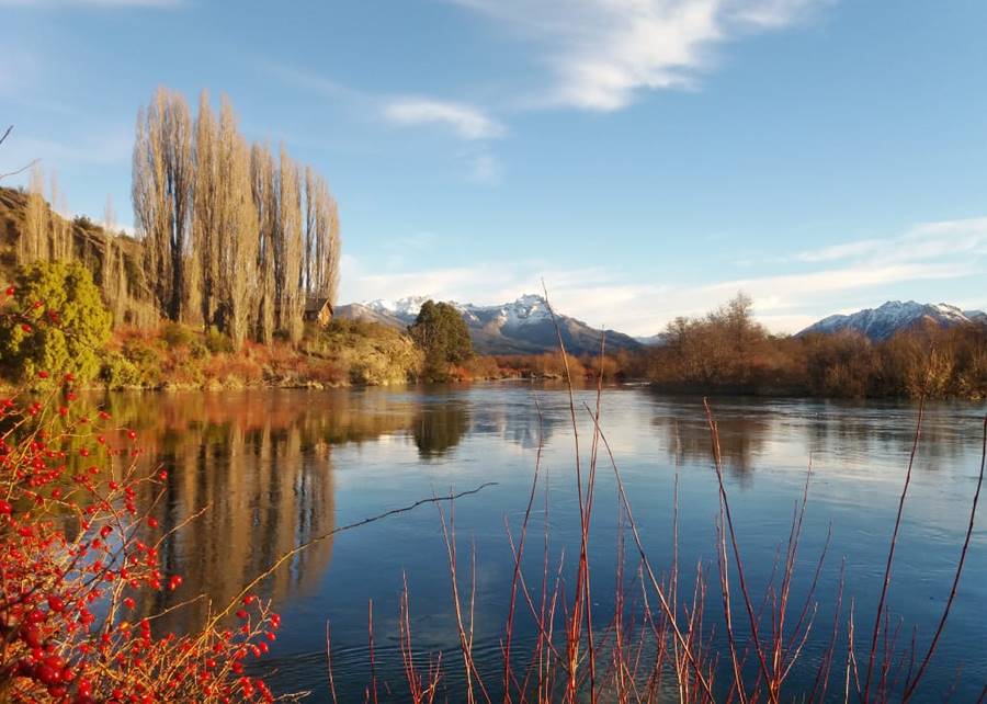 Placid waters of lake Pellegrini, snow capped mountains and forests in Cholila