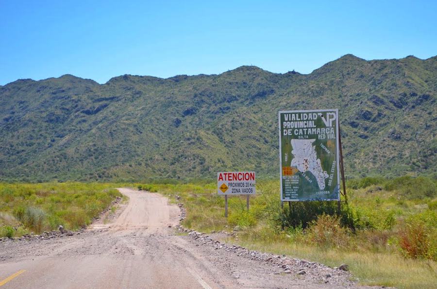 fin del pavimento fin del asfalto, la ruta sigue de ripio montañas y arbustos y un cartel vial