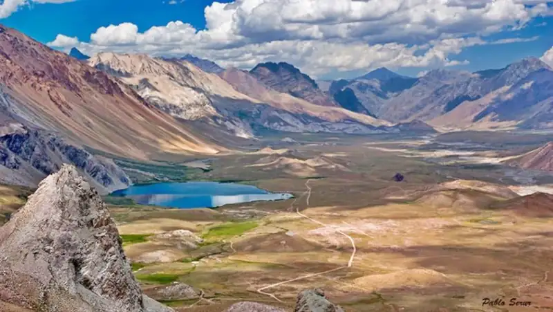 Valle rodeado de altas montañas con una laguna